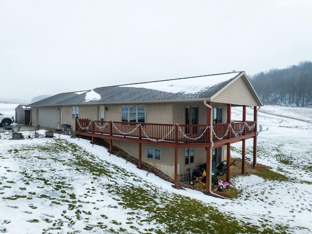 snow covered back of property with a garage