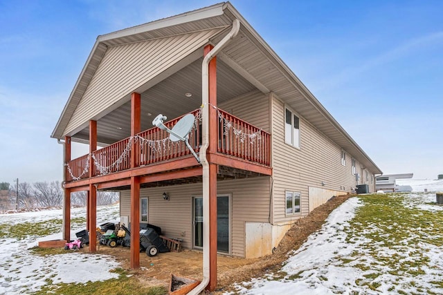 snow covered back of property with a deck