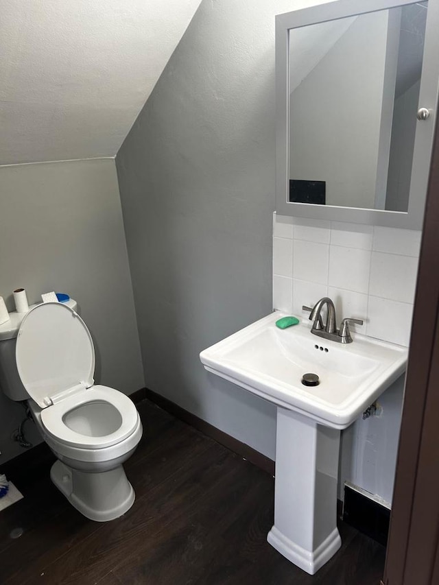 bathroom featuring tasteful backsplash, hardwood / wood-style floors, lofted ceiling, and toilet