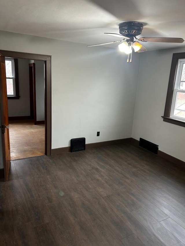 empty room with ceiling fan and dark hardwood / wood-style flooring