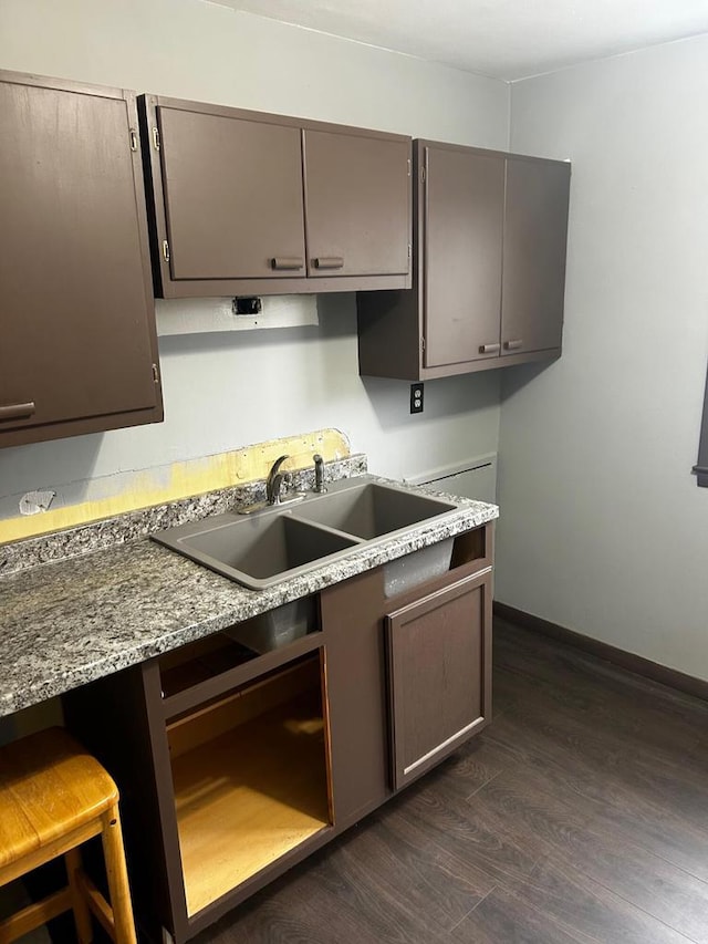 kitchen with dishwasher, a kitchen breakfast bar, sink, dark hardwood / wood-style floors, and light stone counters