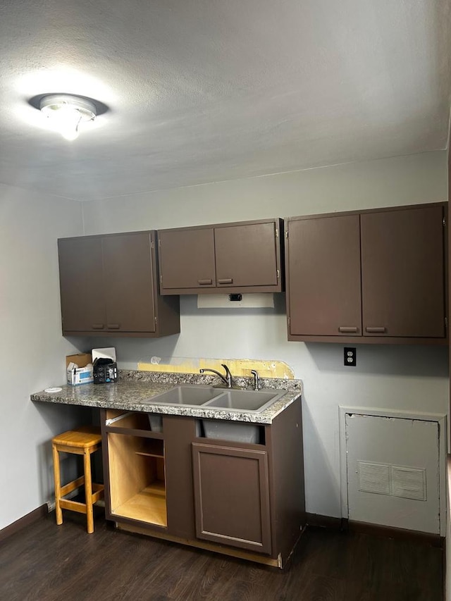 kitchen with dark brown cabinetry, sink, dark wood-type flooring, and a textured ceiling