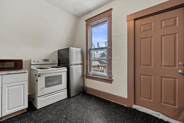 kitchen with electric range, white cabinetry, stainless steel refrigerator, and lofted ceiling