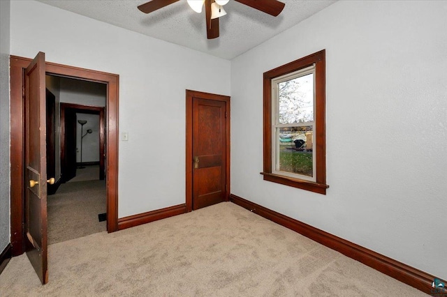 unfurnished bedroom with a textured ceiling, ceiling fan, and light carpet