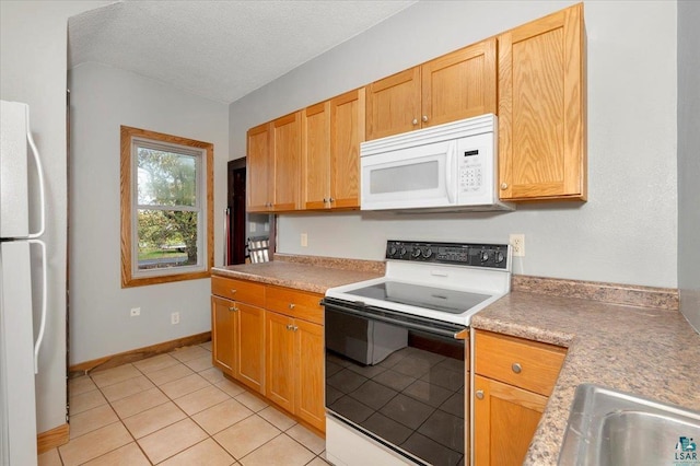 kitchen featuring a textured ceiling, white appliances, and light tile patterned flooring