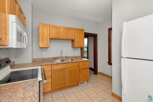 kitchen featuring a textured ceiling, white appliances, sink, and light tile patterned floors