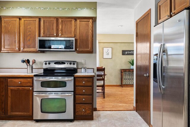 2022 27th St, Monroe, WI 53566 - kitchen featuring brown cabinetry, light tile patterned floors, appliances with stainless steel finishes, and light countertops