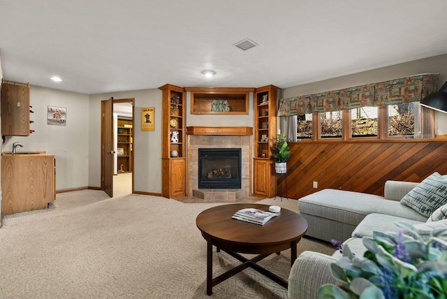2022 27th St, Monroe, WI 53566 - living room with visible vents, baseboards, a tiled fireplace, light colored carpet, and wood walls