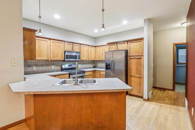 kitchen with tasteful backsplash, light hardwood / wood-style flooring, hanging light fixtures, and appliances with stainless steel finishes