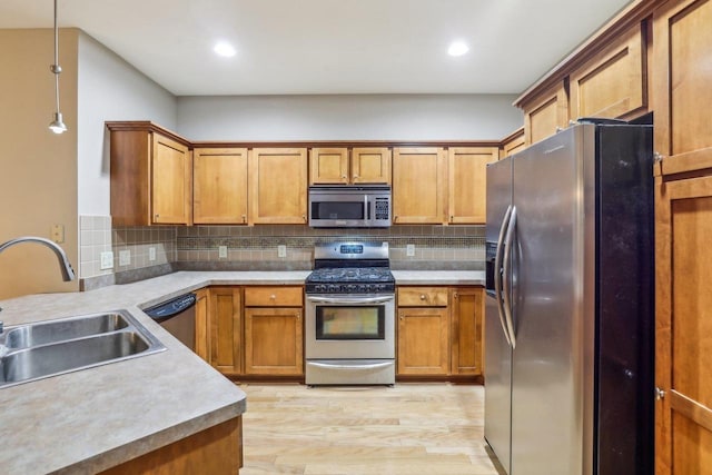 kitchen featuring pendant lighting, sink, appliances with stainless steel finishes, tasteful backsplash, and light hardwood / wood-style floors