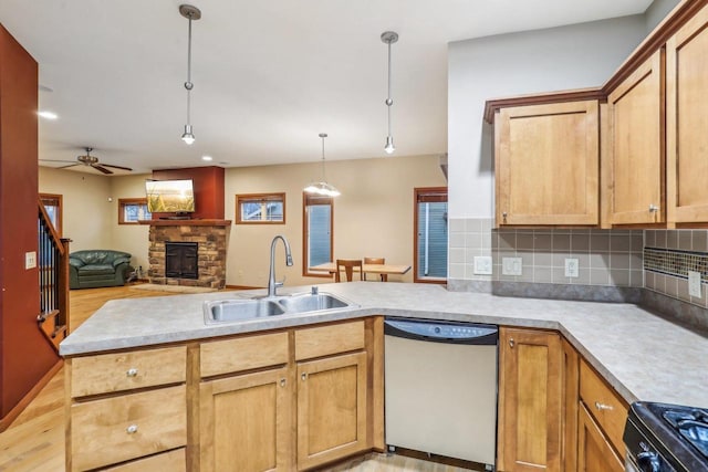 kitchen featuring sink, hanging light fixtures, stainless steel dishwasher, a fireplace, and kitchen peninsula