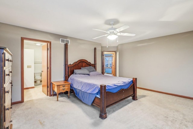 bedroom with ceiling fan, light colored carpet, and ensuite bath