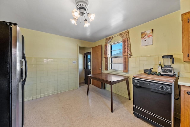 interior space with tile walls, stainless steel refrigerator with ice dispenser, and black dishwasher