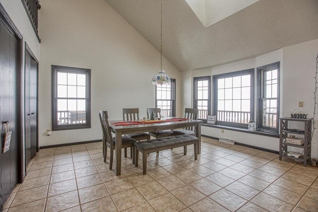 tiled dining area featuring high vaulted ceiling