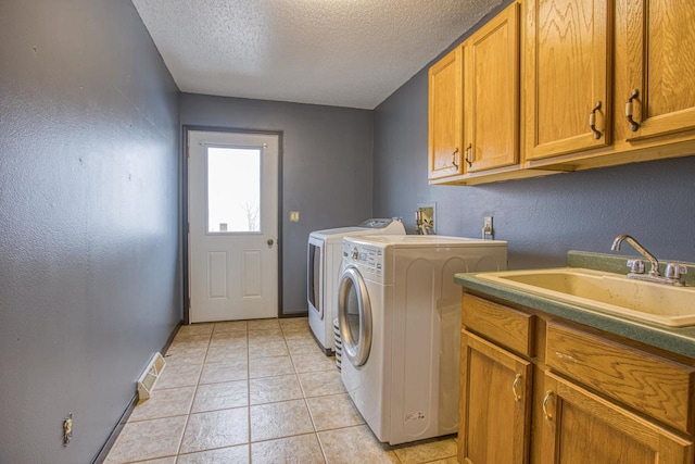 laundry area featuring cabinets, sink, independent washer and dryer, a textured ceiling, and light tile patterned flooring