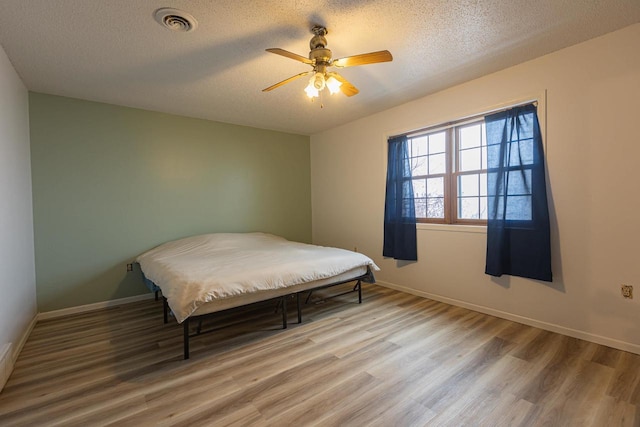 bedroom featuring ceiling fan, a textured ceiling, and hardwood / wood-style flooring