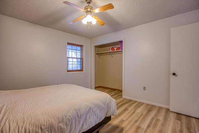 bedroom featuring ceiling fan, light hardwood / wood-style flooring, a textured ceiling, and a closet