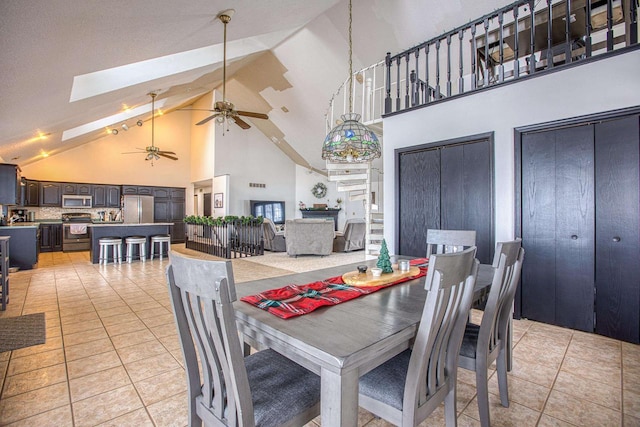 tiled dining room with a skylight, ceiling fan, and high vaulted ceiling