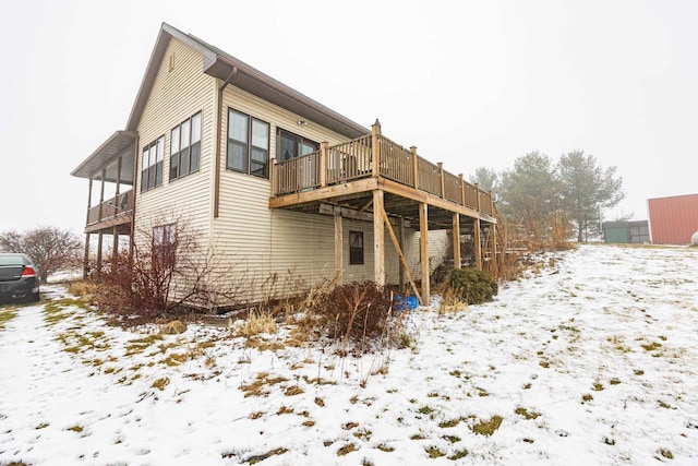 snow covered rear of property with a deck