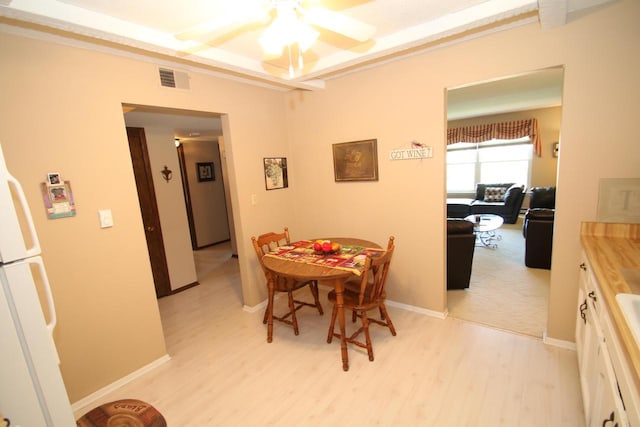 dining room with a tray ceiling, ceiling fan, and light hardwood / wood-style floors