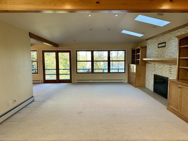N7859 Lakeside Park Rd, Elkhart Lake, WI 53020 - unfurnished living room featuring a brick fireplace, lofted ceiling with skylight, a baseboard radiator, and light colored carpet