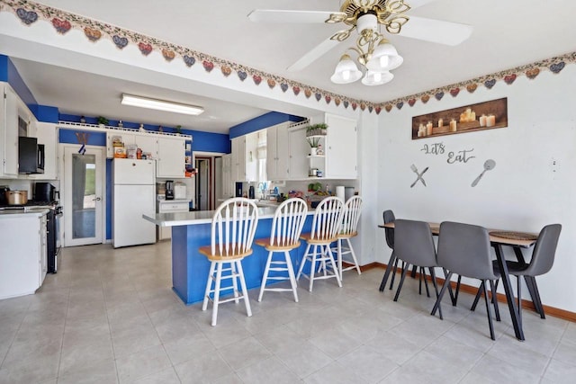 kitchen featuring white cabinets, ceiling fan, white refrigerator, and range with gas stovetop