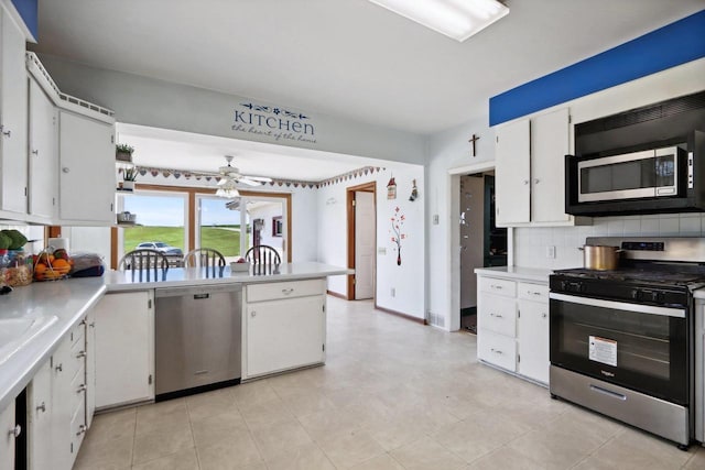 kitchen featuring decorative backsplash, white cabinets, stainless steel appliances, and ceiling fan