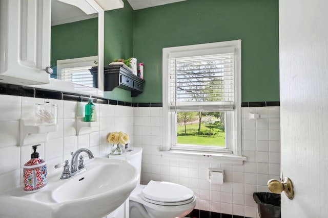 bathroom with toilet, tile walls, and sink