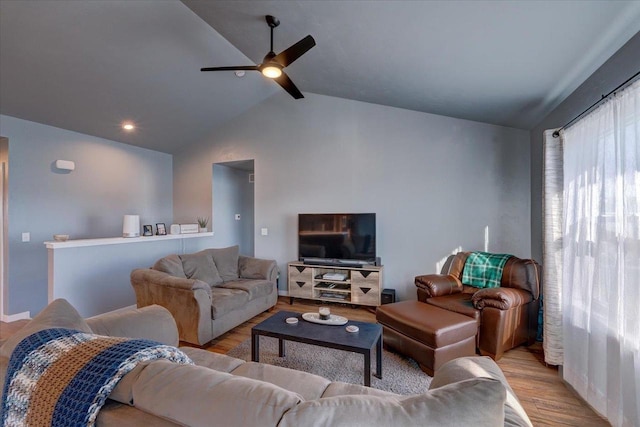 living room featuring ceiling fan, light hardwood / wood-style floors, and vaulted ceiling