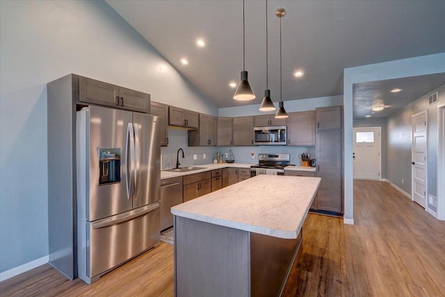 kitchen with a center island, sink, hanging light fixtures, light hardwood / wood-style flooring, and stainless steel appliances