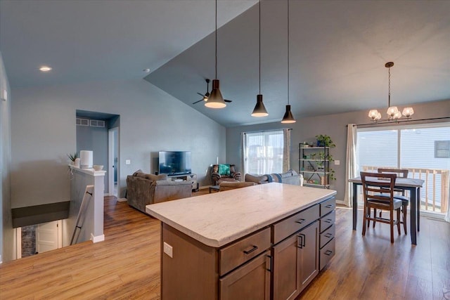 kitchen featuring a center island, an inviting chandelier, hanging light fixtures, vaulted ceiling, and light wood-type flooring