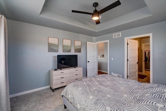 carpeted bedroom featuring a tray ceiling and ceiling fan