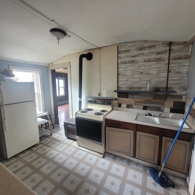 kitchen with white appliances, vaulted ceiling, and sink