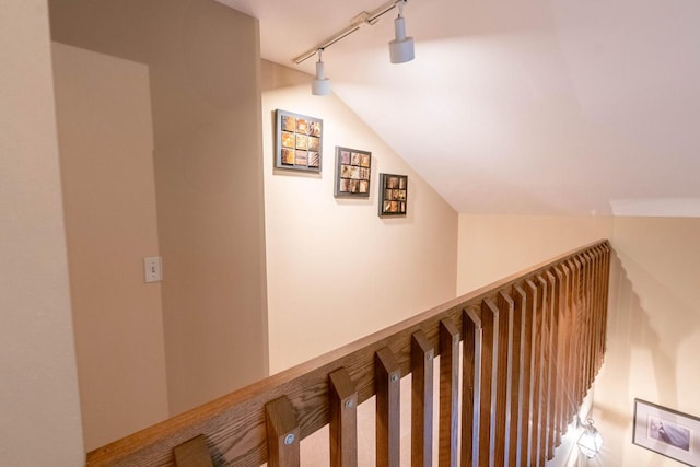 hall with vaulted ceiling and track lighting