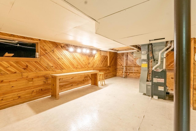 basement featuring heating unit and wood walls