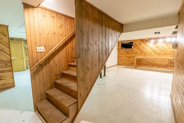 stairway featuring wooden walls