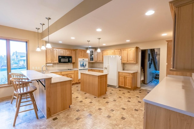 kitchen with a kitchen bar, light brown cabinetry, black appliances, pendant lighting, and a kitchen island