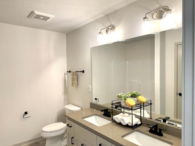 bathroom featuring walk in shower, vanity, a textured ceiling, and toilet