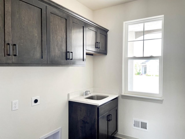 washroom with hookup for an electric dryer, cabinets, and sink