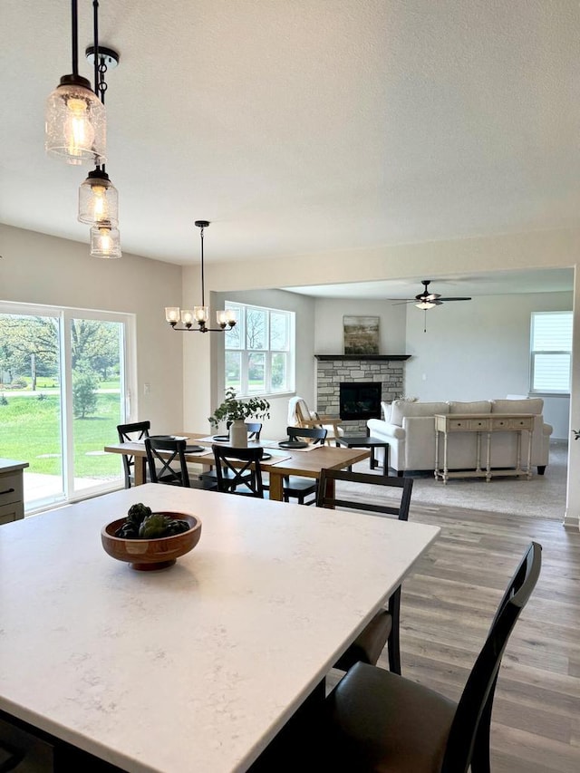 kitchen featuring a wealth of natural light, a fireplace, pendant lighting, and ceiling fan with notable chandelier