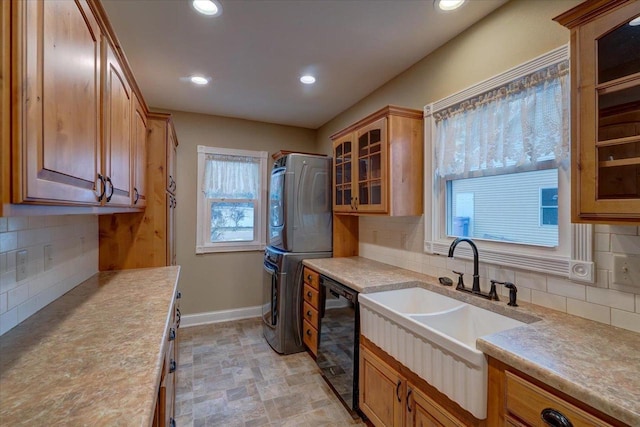 kitchen with tasteful backsplash, sink, dishwasher, and stacked washing maching and dryer