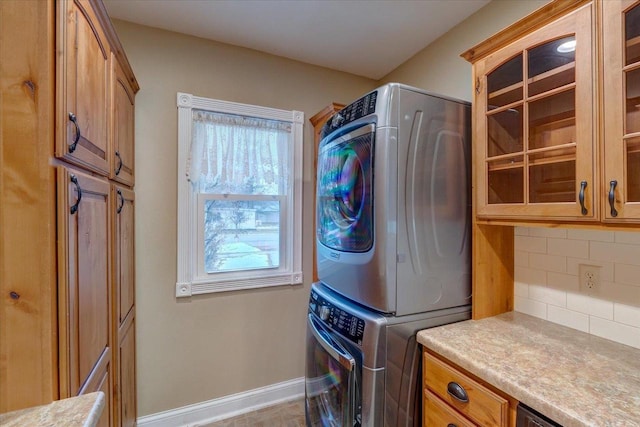 laundry area featuring cabinets and stacked washer and clothes dryer