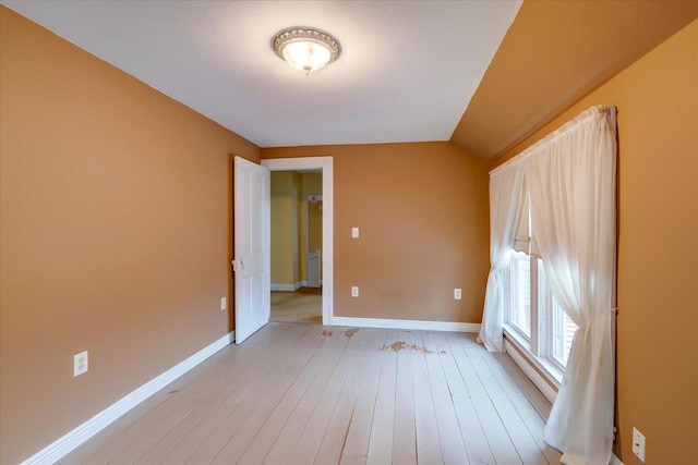 unfurnished room with lofted ceiling and light wood-type flooring