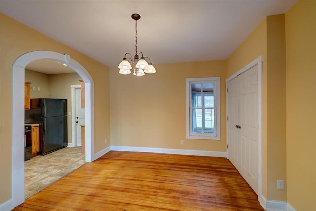 unfurnished dining area with a notable chandelier and light hardwood / wood-style floors