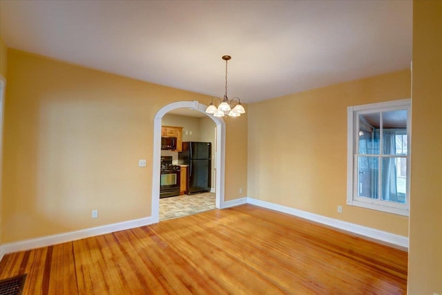 unfurnished dining area with hardwood / wood-style flooring and a notable chandelier