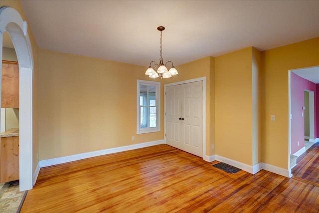 unfurnished dining area with hardwood / wood-style flooring and a chandelier