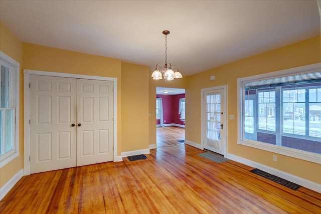 unfurnished dining area featuring hardwood / wood-style flooring and a chandelier