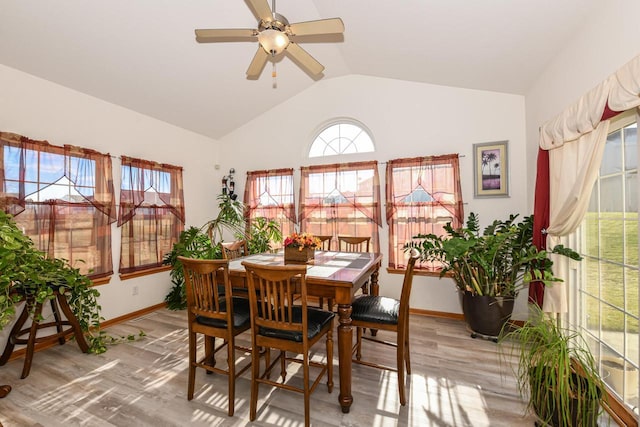 dining room with ceiling fan, wood-type flooring, and vaulted ceiling