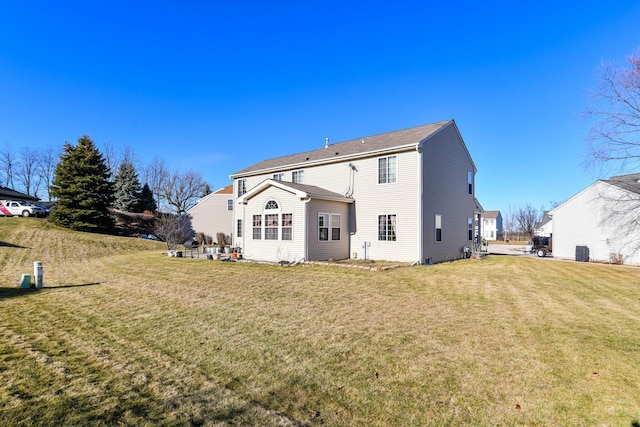 rear view of property featuring central air condition unit and a lawn