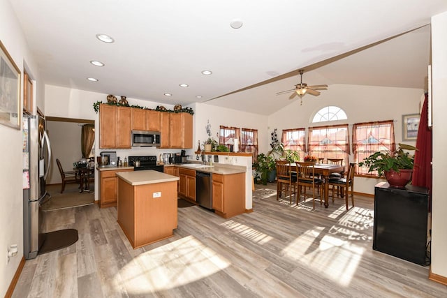 kitchen featuring ceiling fan, sink, black appliances, a center island, and light hardwood / wood-style floors